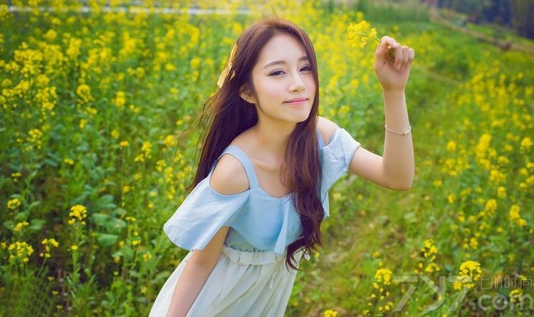 接近黄昏的阳光照亮了整片黄花，生机盎然的绿叶和花朵在风中微微摇曳着，迎合着女子翩跹的裙角。一席长裙甜美优雅，棕色的长卷发和露出香肩的雪纺，让她美丽的如同花仙子般。下面一起来看看清纯美女生活照图片，绿草映衬柔情花仙子。